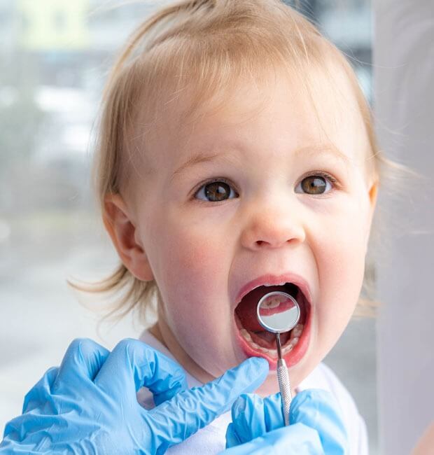 A toddler at his first dentist appointment, having his teeth checked