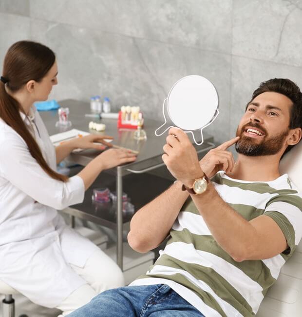 Patient checking his teeth after having dental crowns put in