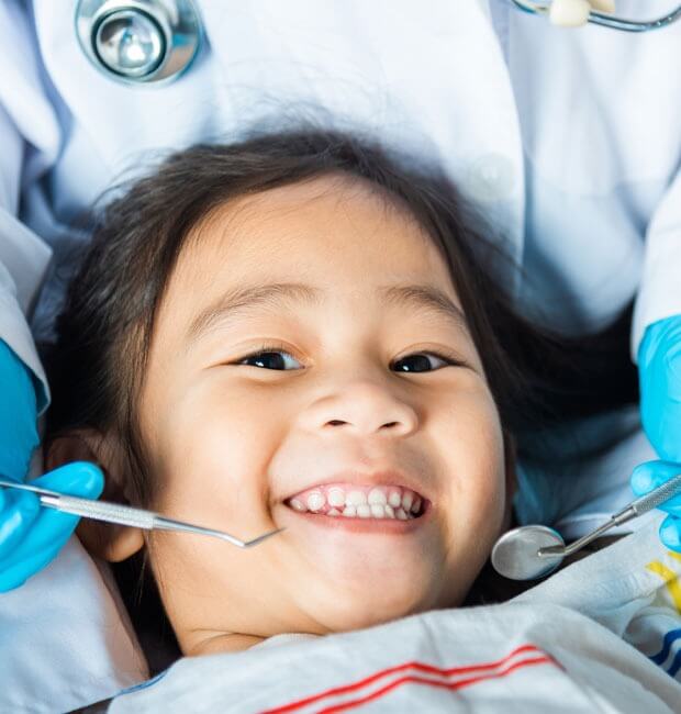 Smiling child as the dentist is checking his teeth