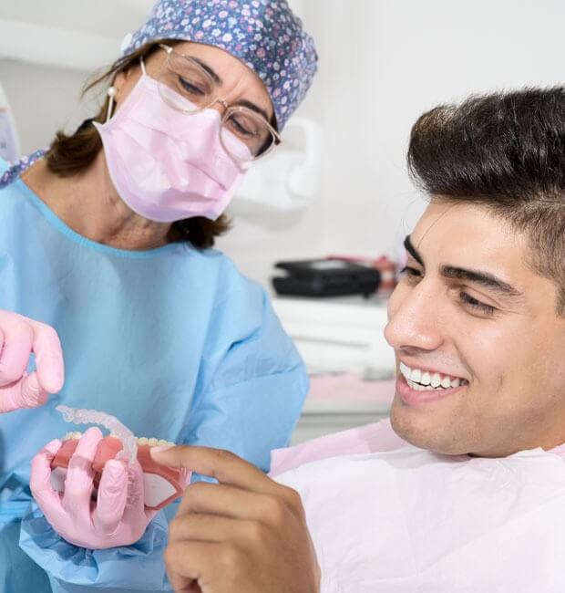 Dentist showing male patient how Invisalign works with your teeth