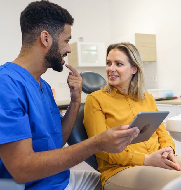 Dentist showing female patient how the adult orthodontics will work with her teeth