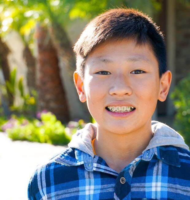 A teen boy smiling outside with braces