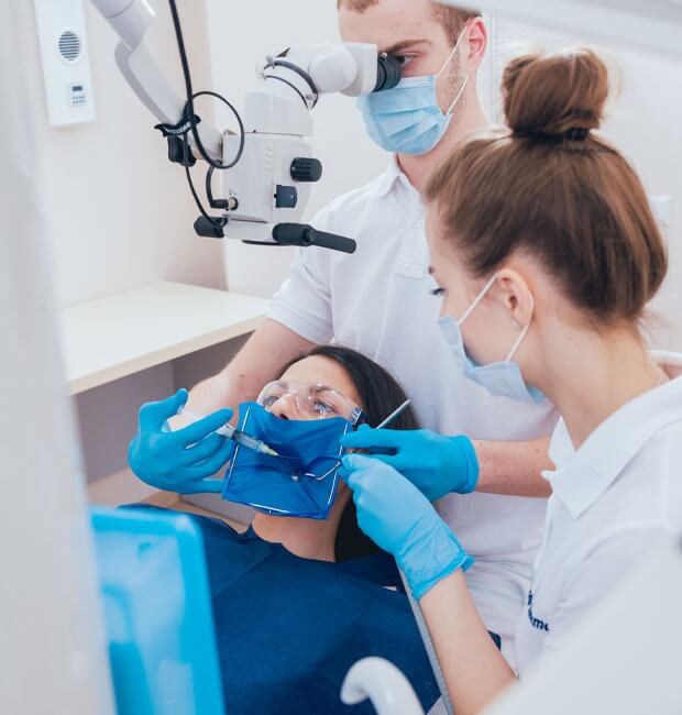 Dentist performing a root canal on a female patient