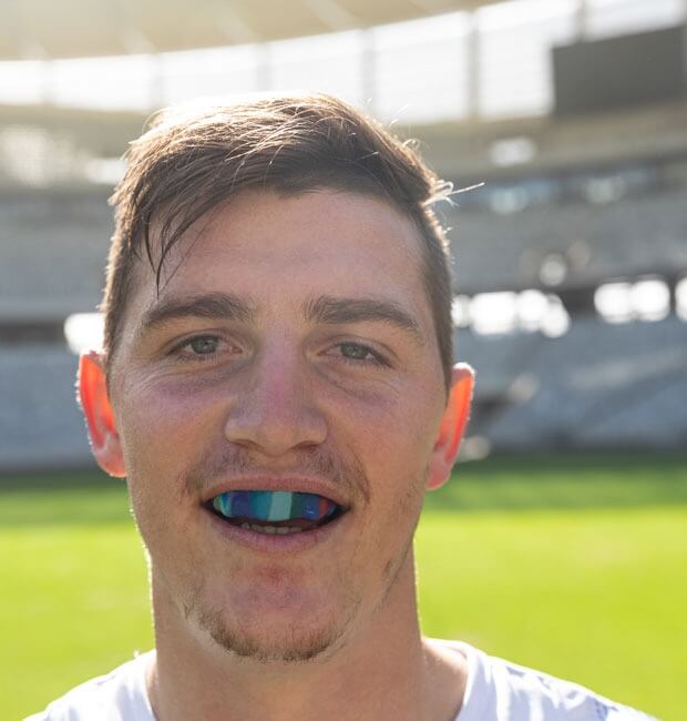 A ruby player smiling with his mouthguard in position