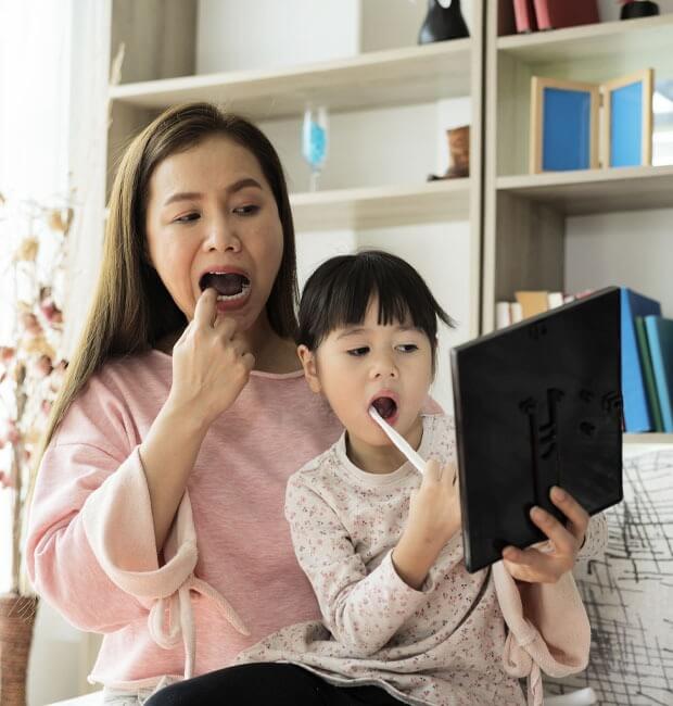 Mother and her daughter watching a video on how to brush your teeth properly