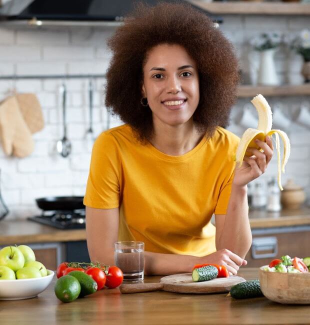 A smiling patient with white teeth enjoying a banana